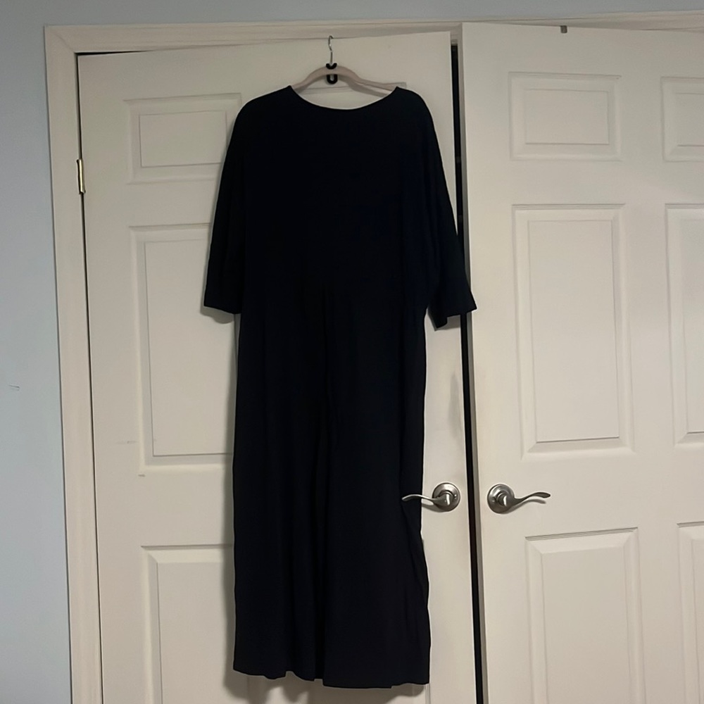 Black jumpsuit with 3/4 sleeves and wide legs. Eyelet loop closer.